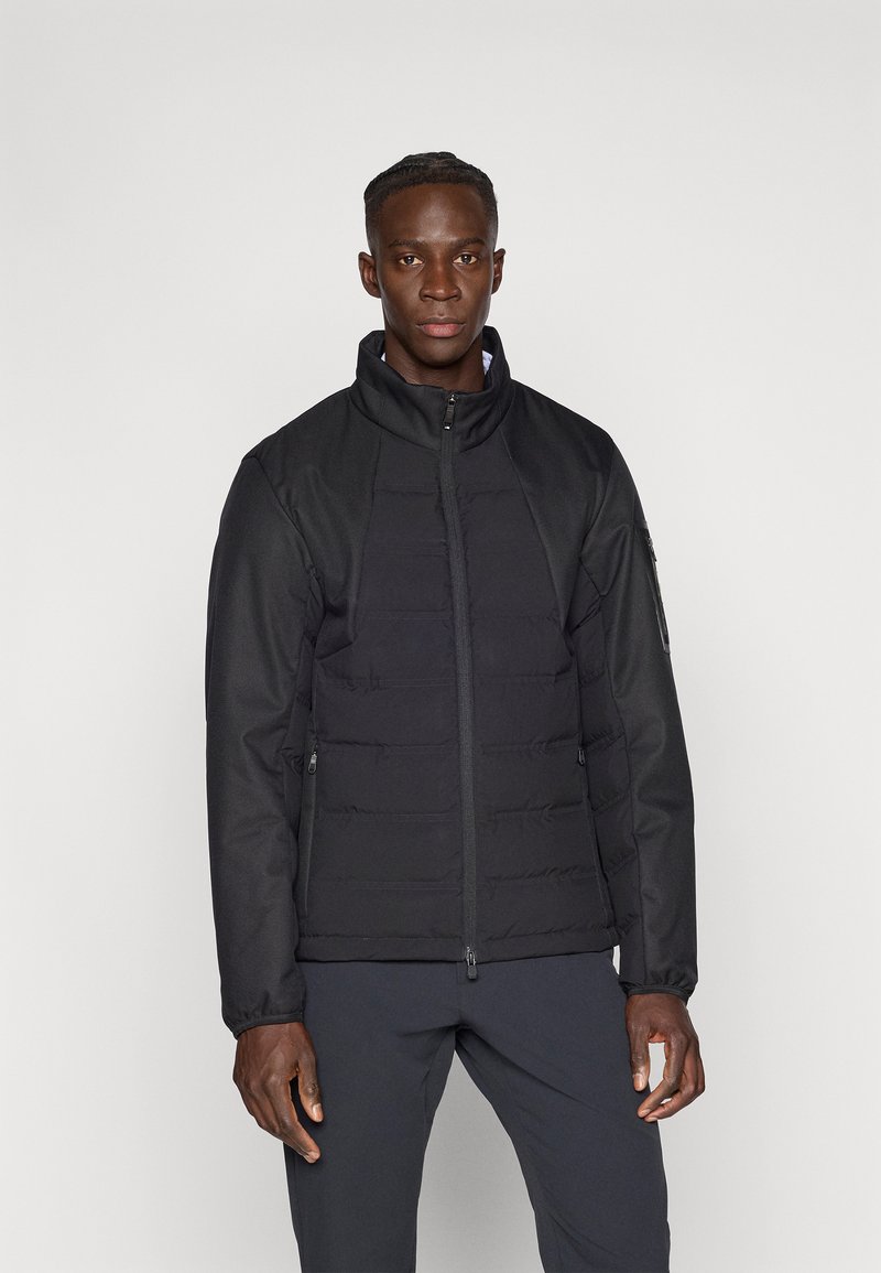 Μαύρο μπουφάν με επένδυση, ψηλό γιακά, κλείσιμο με φερμουάρ και δύο πλαϊνές τσέπες, με λεία υφή και μινιμαλιστικό σχεδιασμό.