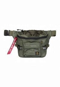 Borsetă de talie verde măslinie realizată din material durabil. Are un buzunar frontal cu fermoar, secțiune superioară din plasă, bretele reglabile și o etichetă cu accente roșii.