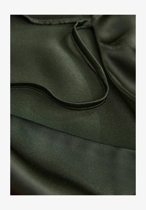 Ciemnozielony satynowy materiał o gładkiej fakturze, z wyraźnymi zakrzywionymi liniami i kontrastowymi matowymi obszarami, podkreślający płynny design i warstwowość.