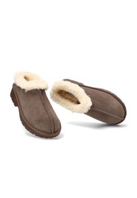 Zapatillas de ante marrón con un grueso forro de piel de color crema, estilo de poner y suelas de goma para comodidad y calidez en interiores.