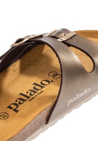 Gros plan sur une sandale Palado marron avec deux sangles métalliques réglables et un pied en liège texturé.