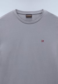 Gray cotton t-shirt featuring a crew neck and a small embroidered flag detail. Smooth texture, simple design with no additional accents.