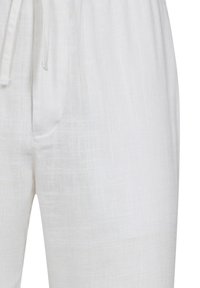 Witte linnen broek met een ontspannen pasvorm, voorzien van een elastische tailleband, een trekkoord en een subtiele textuur.
