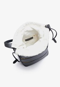 Musta nahkainen ämpärilaukku, jossa on valkoinen puuvillavuori. Sisältää nyörisulkeutuvan pääsyn, kaksi mustaa nahkaremmiä ja metallisia yksityiskohtia.