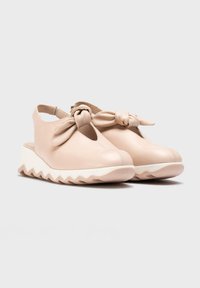 Zapatos slingback de cuero beige con un acento de lazo, que presentan una punta redondeada y una suela de cuña en zigzag blanca. Textura suave, diseño minimalista.