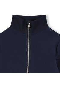 Mørkeblå zip-jakke med høy krage og glatt, elastisk stoff. Metallglidelås går ned foran og står i kontrast til materialet.