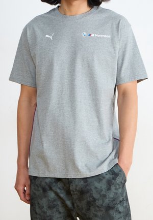 T-shirt grigio a maniche corte realizzato in un tessuto morbido, con dettagli del logo di Puma e BMW Motorsport, orlo leggermente curvo e rifinitura laterale viola.