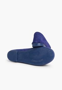 Blå ruskinds slip-on sko med en tekstureret gummisål, der har en rund tå og minimale syninger.