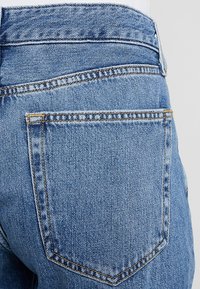 Světle modré džínové kalhoty s těsným střihem, které mají dvě zadní kapsy a kontrastní švy podél švů.