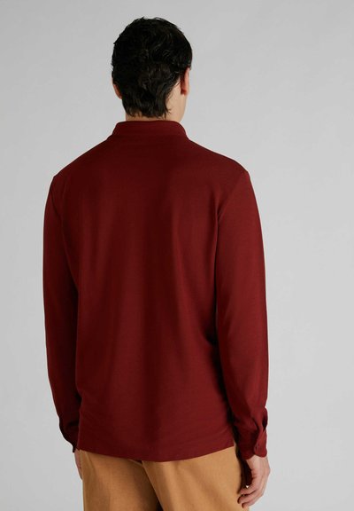 Polo shirt a maniche lunghe di colore bordeaux con una texture liscia, dotato di colletto e polsini con bottoni. La vista posteriore mostra una vestibilità rilassata.