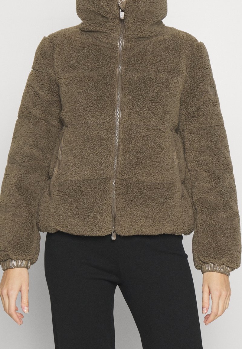 Giacca in pile marrone con cappuccio, chiusura con zip frontale e polsini elasticizzati. Presenta una superficie texturizzata e tasche laterali.