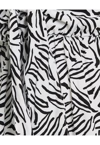 Čierno-biele zebra vzorované látky s textúrovaným povrchom, s plynulými líniami a detailom zhrnutého pásu.