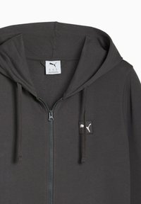 Mørkegrå zip-up hættetrøje lavet af blødt stof, med et lille logo-patch på venstre bryst og snørre til hætten.
