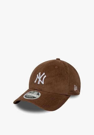 Brown corduroy cap with white embroidered NY logo, curved brim, textured fabric, and adjustable strap. New Era branding on side.