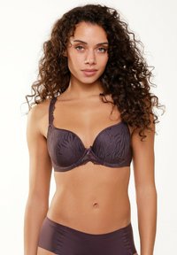 Reggiseno viola con coppe sagomate e un sottile motivo a zebra, rifinito con pizzi sugli spallacci e un fiocco di raso al centro.