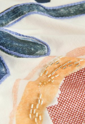 Ziedu raksta audums ar ziliem un oranžiem akcentiem, kam ir strukturēta virsma un zelta pērlītes, kas iešūtas dizainā.