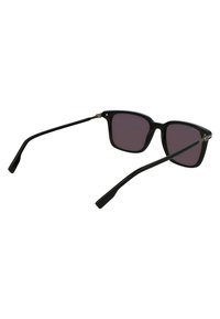 Ochelari de soare cu ramă pătrată neagră, cu lentile întunecate și brațe înguste. Fabricati din plastic cu finisaj mat și accente metalice la balamale.