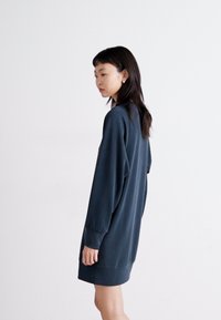 Σκούρο μπλε φόρεμα με φούτερ, με μακριά μανίκια, άνετη εφαρμογή, στρογγυλή λαιμόκοψη και μαλακή υφή, φτάνει πάνω από τα γόνατα. Απλός σχεδιασμός.