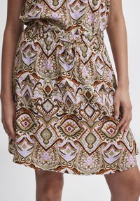Floral-patterned skirt featuring green, brown, and pink hues. Made from lightweight fabric with an elastic waistband and drawstring detail.