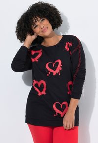 Zwart sweatshirt met een spuitverfontwerp van een rode hart, met lange mouwen en een comfortabele pasvorm. Accenten zijn onder andere rode stiksels op de schouder.
