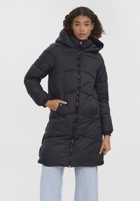 Manteau long noir rembourré avec capuche, présentant un zip à l'avant, deux poches latérales et un design matelassé avec une texture lisse.