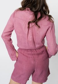 Rompere in lino rosa con maniche lunghe, vita elastica e pantaloni coordinati. Tessuto testurizzato con una vestibilità rilassata, vista posteriore.