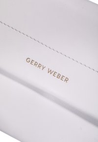 Vit läderplånbok med präglad "GERRY WEBER"-logotyp i guld. Har slanka sömmar och en mjuk yta som framhäver dess minimalistiska design.