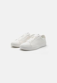 Baskets blanches avec un dessus en tissu lisse, bout rond et design à lacets. Caractéristiques d'une semelle blanche solide et d'un accent subtil au niveau du talon.