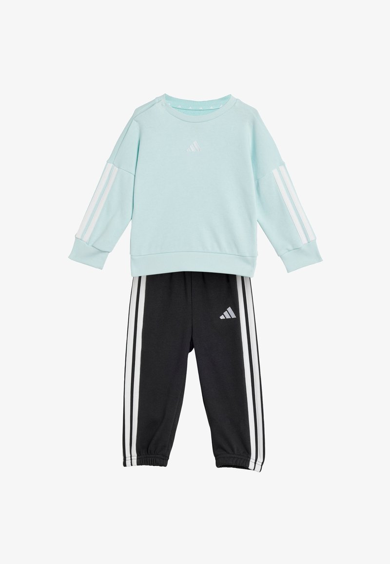 Sudadera azul claro con rayas blancas en las mangas y pantalones de chándal negros con rayas blancas y logo. Tejido suave, corte relajado, puños elásticos.