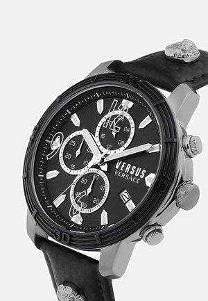 Černo-stříbrné chronografické hodinky Versus Versace s třemi subciferníky, datumovým okénkem, texturovaným páskem a motivem lebky na řemínku.