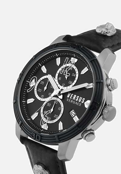 Montre chronographe noire avec un bracelet en silicone texturé noir, des accents argentés et un boîtier rond. Elle dispose de trois sous-cadrans et d'une fenêtre de date.