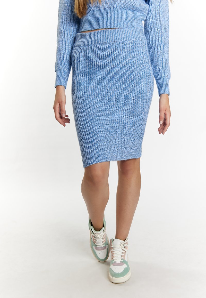 Blauwe rib gebreide rok met een hoge tailleband, gecombineerd met wit en pastelgroene sneakers. Gladde textuur en aansluitende silhouet.