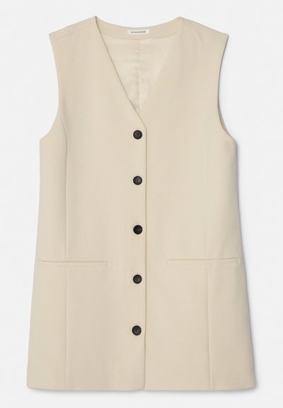 Beige, varrukateta vest, millel on V-kujuline kaelus, kuus musta nuppu ees ja kaks horisontaalset taskut. Lihtne tekstuur.