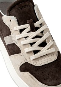 Baskets en suède marron avec un panneau beige clair comportant des perforations et des lacets assortis. Elles disposent d'une semelle en caoutchouc blanche et d'un logo embossé.