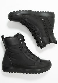 Bottines noires avec dessus synthétique lisse, design à lacets, col rembourré, accents texturés et semelle robuste pour une meilleure adhérence.