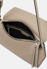 Beige Lederhandtasche mit glatter Textur, ausgestattet mit einem Reißverschlussfach, schlankem silberfarbenem Zubehör und einer strukturierten rechteckigen Form.