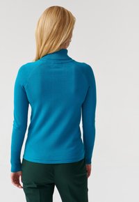 Pull à col roulé turquoise avec manches longues, col côtelé et design élégant et ajusté. Le matériau semble doux et lisse.