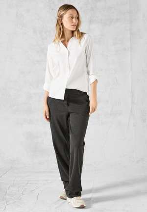 Witte button-up shirt met opgerolde mouwen en grijze broek. Lichtgewicht stof, relaxte pasvorm, gecombineerd met lichtgekleurde sneakers. Minimalistisch ontwerp.