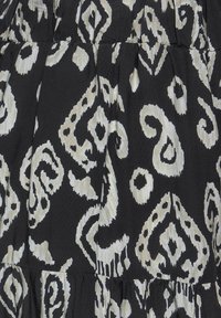 Tissu noir avec un motif cachemire abstrait blanc. Le matériau présente une légère texture et comporte des volants superposés.
