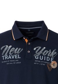 Marineblauw polo shirt met een kraag, voorzien van witte en oranje accenten, afgewerkt met geprinte tekst "New Travel York Guide" en een logo patch.