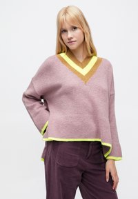 Puha rózsaszín kötött V-nyakú pulóver kontrasztos barna és neon sárga részletekkel. Laza szabású, oldalán sliccel a szegélynél.