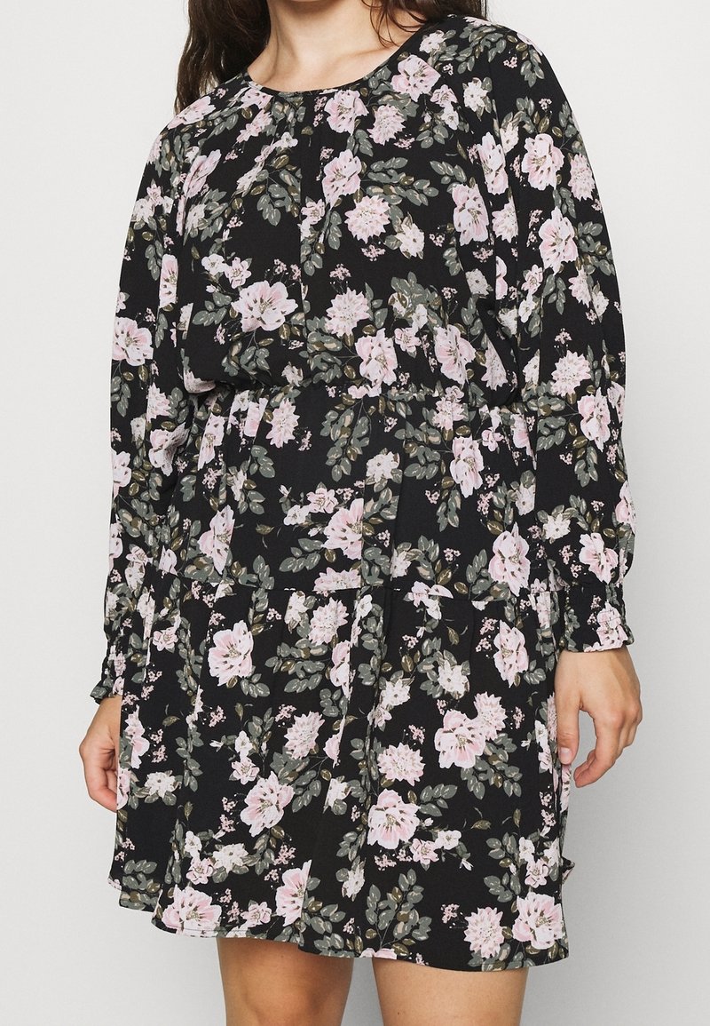 Schwarzes Kleid mit floralem Muster aus pinken und weißen Blumen sowie grünen Blättern. Lange Ärmel, geraffte Taille und lockere Passform.