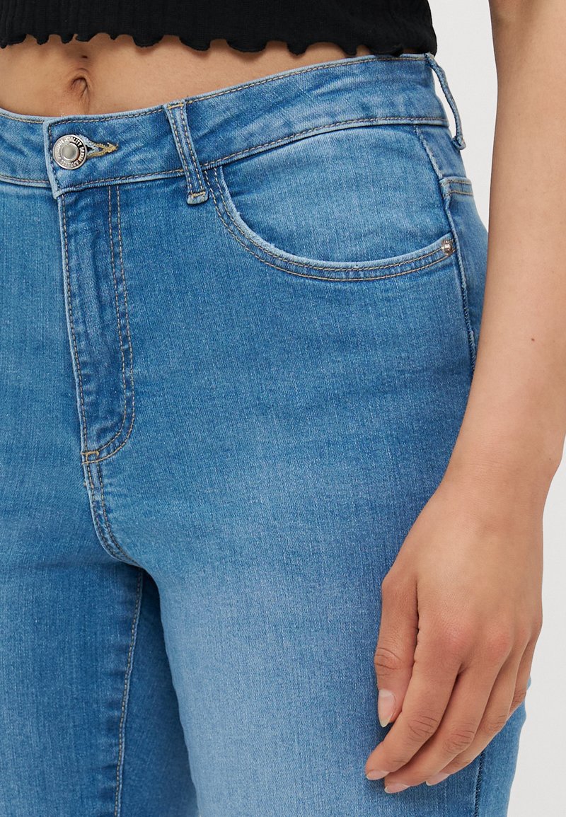 Blaue Denim-Jeans mit einem klassischen Fünf-Taschen-Design, leichter Ausbleichung und einem Knopfverschluss an der Taille. Glatte Textur und gerade Passform.