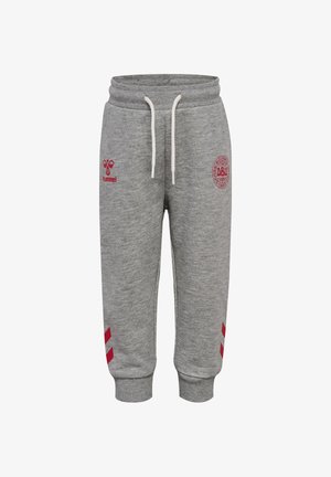 Szare spodnie dresowe dla malucha z elastycznym pasem, białymi sznurkami, czerwonym logo hummel na lewym udzie, emblematem klubu sportowego na prawym udzie oraz czerwonymi znakami w kształcie strzałek przy mankietach.