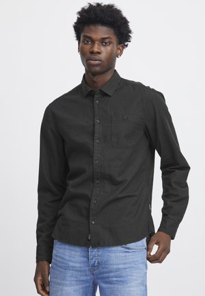 Schwarz, langärmliges Hemd aus Baumwolle mit einem Button-Down-Kragen, einer Brusttasche und einem geraden Saum, kombiniert mit hellblauen Jeans.