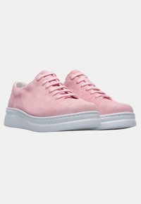 Pink suede sneakers with a smooth white rubber sole and matching laces. Rounded design with subtle stitching details on the upper.