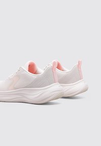 Zapatillas de malla blanca con un acabado texturizado. Presenta acentos en rosa en el talón y la lengüeta. Diseño de suela curvada para mayor amortiguación.