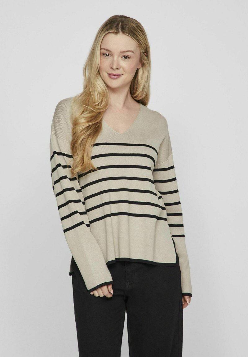 Maglione beige a scollo a V con strisce orizzontali nere, maniche lunghe e vestibilità rilassata. Realizzato in materiale morbido con una texture liscia.