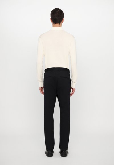 Vit långärmad skjorta med krage; svarta byxor; slim fit; slät textur; svart bälte; enfärgat; minimalistisk design.