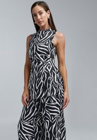 Varrukateta must-valge sebramustriline top, millel on kõrge kaelus ja voogav disain, valmistatud kergest kangast.